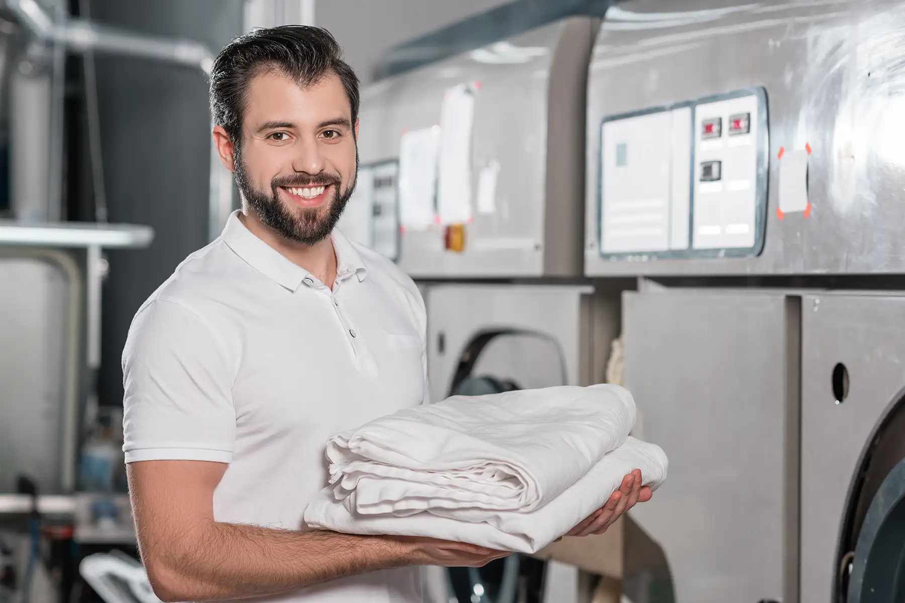 happy dry cleaning worker holding stack of clean clothes