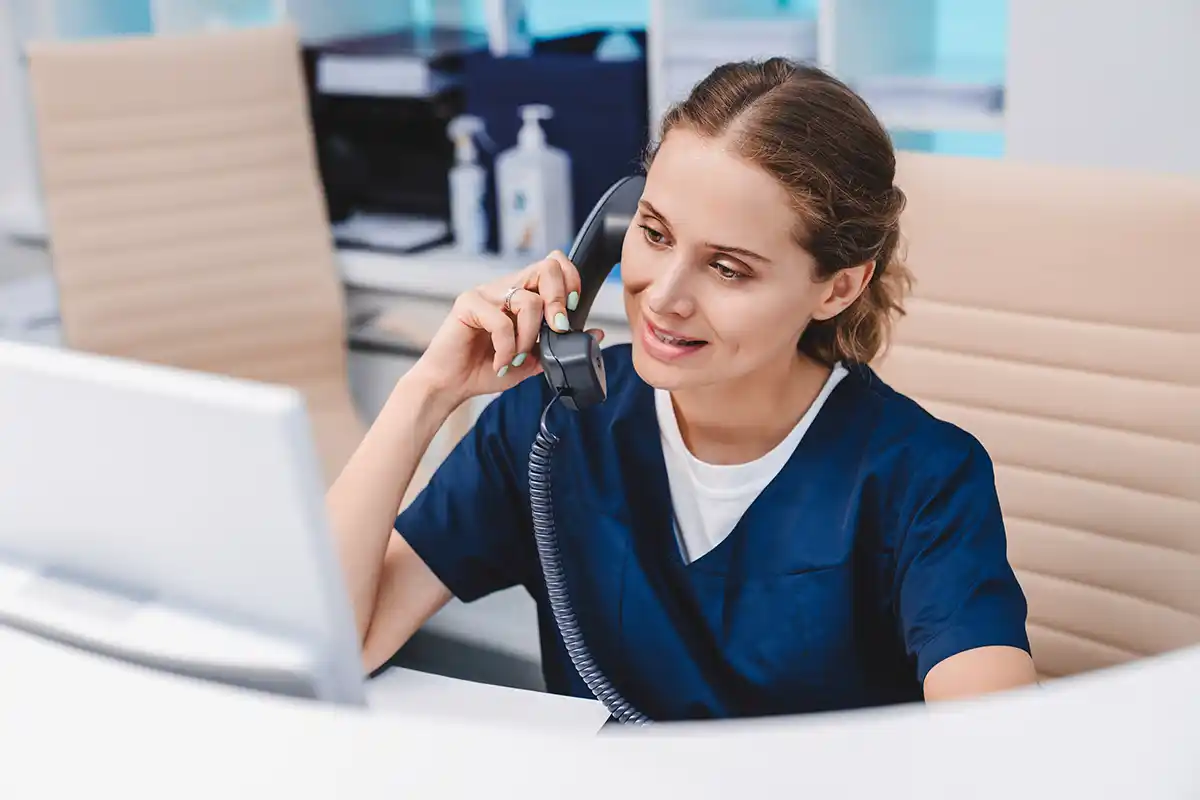 Young female receptionist talking on phone in clinic